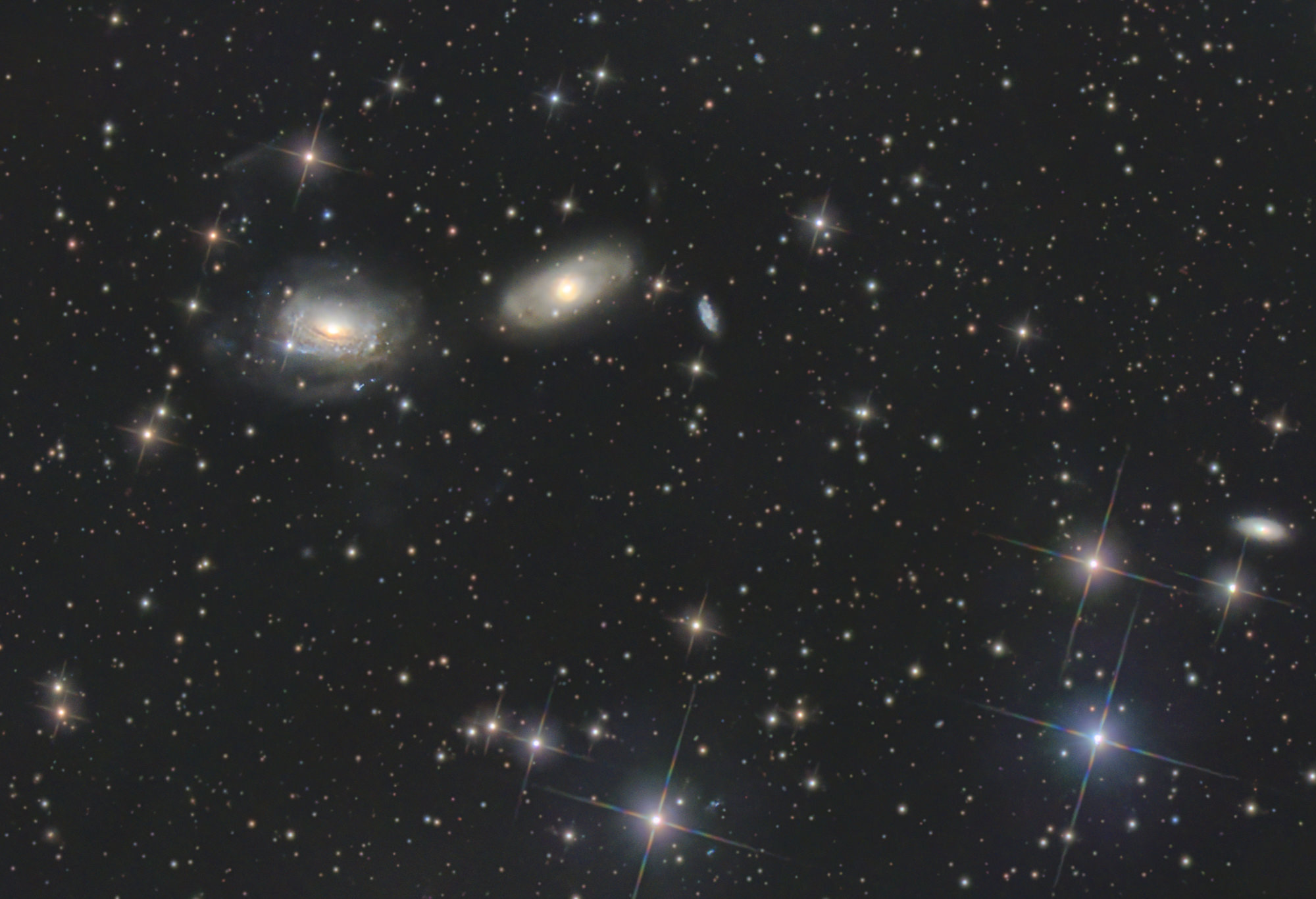 The twisting spiral arms of NGC 3169 (left) have been pulled out into sweeping tidal tails by gravitational interaction with the neighboring galaxy NGC 3166. The two galaxies will eventually merge into one.